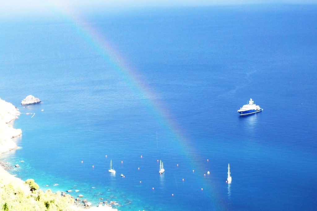 Rainbow over a blue bay with small boats